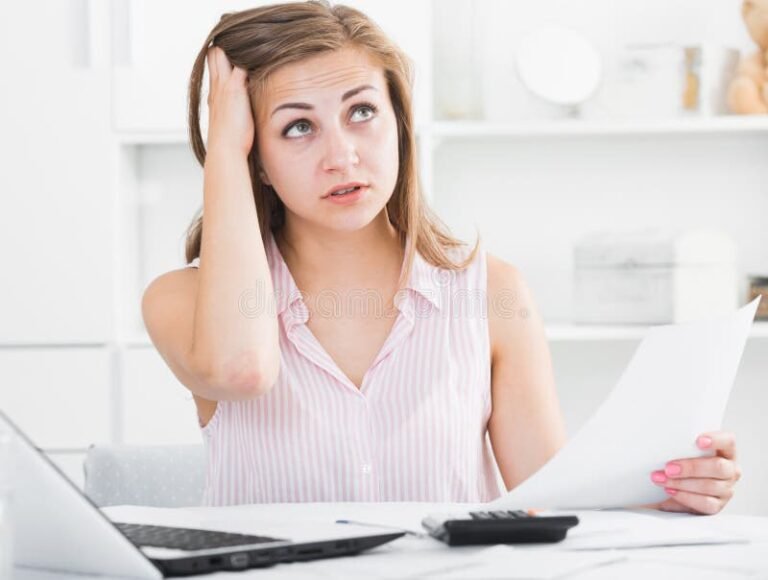 henkilo huolestuneena selaa laskuja poydan aaressa