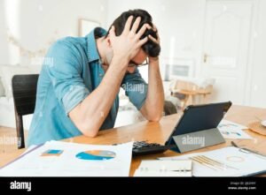 huolestunut henkilo laskujen aarella poydan aaressa