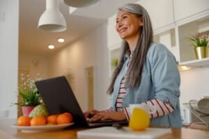 hymyileva henkilo nappaimistolla kotona